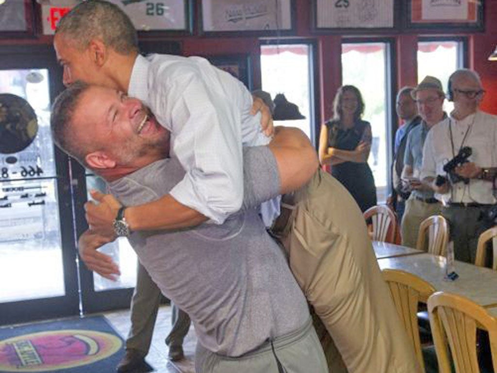 President Barack Obama is hugged by pizza restaurant owner Scott Van Duzer