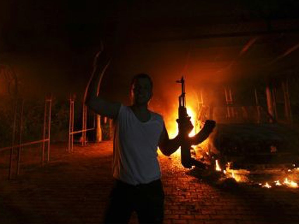 A protester reacts as the US Consulate in Benghazi is seen in flames during a protest by an armed group said to have been protesting a film being produced in the United States