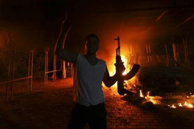 A protester reacts as the US Consulate in Benghazi is seen in flames during a protest by an armed group said to have been protesting a film being produced in the United States