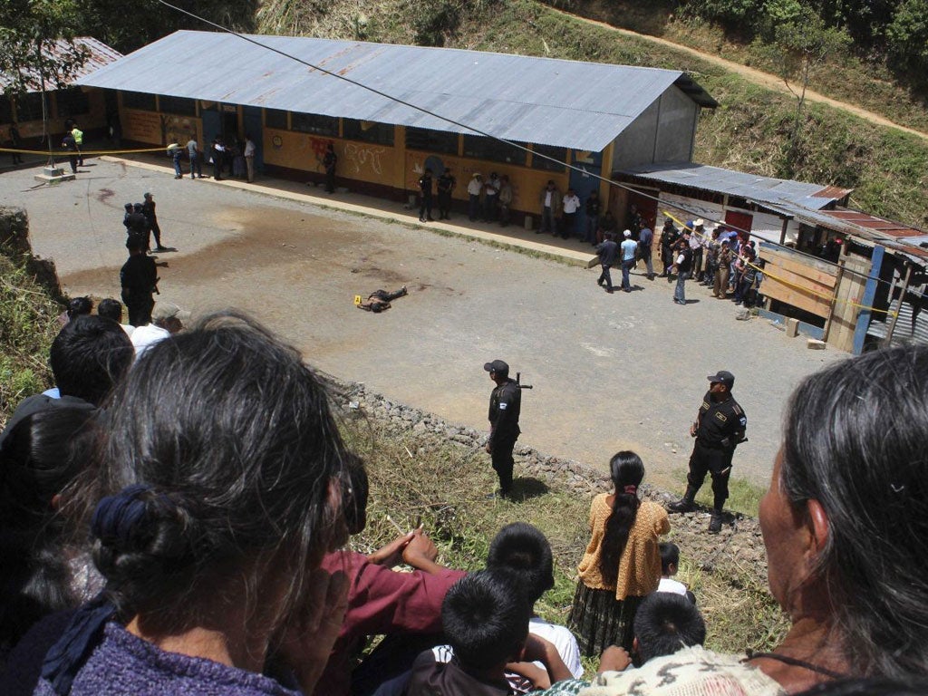 People look at the body of a man who was lynched by a mob inside a public school for allegedly killing two children inside the school in San Juan Tactic, north of Guatemala City,