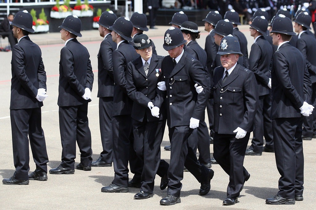 An officer is led away after feeling faint during graduation day at Hendon Police Training Centre