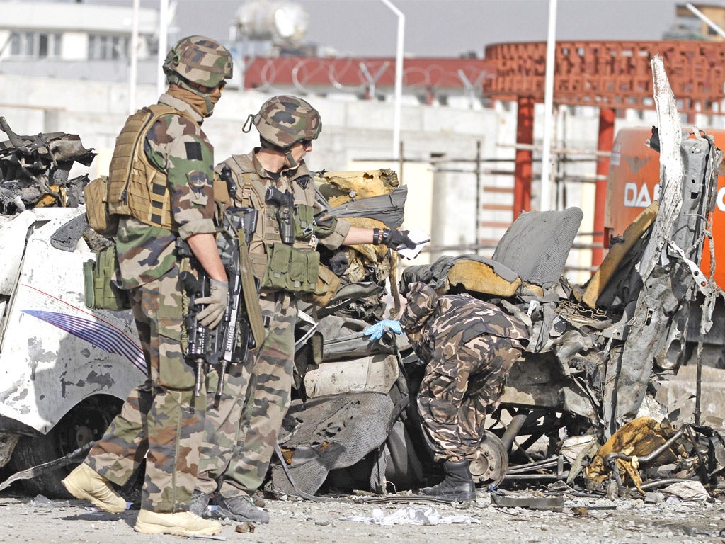 Isaf soldiers survey the wreckage of a minibus destroyed by a suicide bomb in Kabul yesterday. The attack was in response to the anti-Islam film 'The Innocence of Muslims'