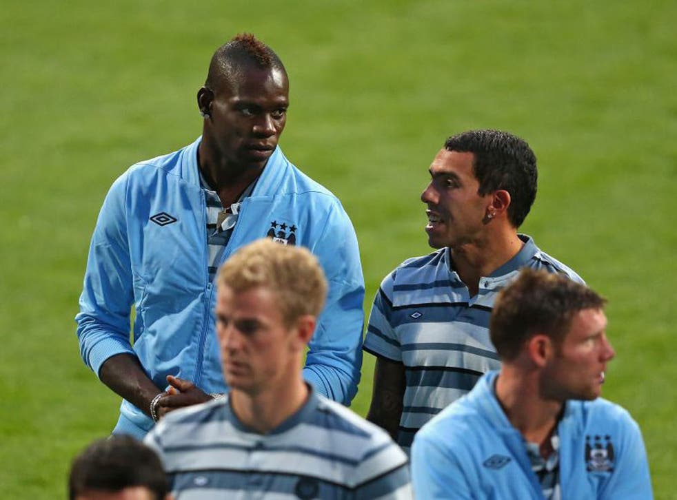 Mario Balotelli (left) chats with Carlos Tevez at the Bernabeu, where he watched the game from the stands