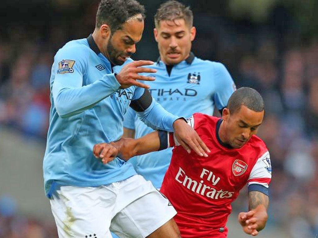 Theo Walcott (right) finds the going tough against Man City
yesterday