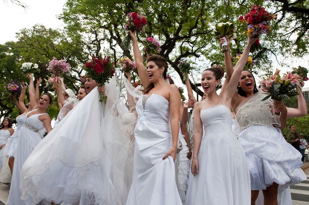 Women in wedding gowns hold up their bouquets as they take part in a bride parade, in Sao Paulo, Brazil, on September 23, 2012.