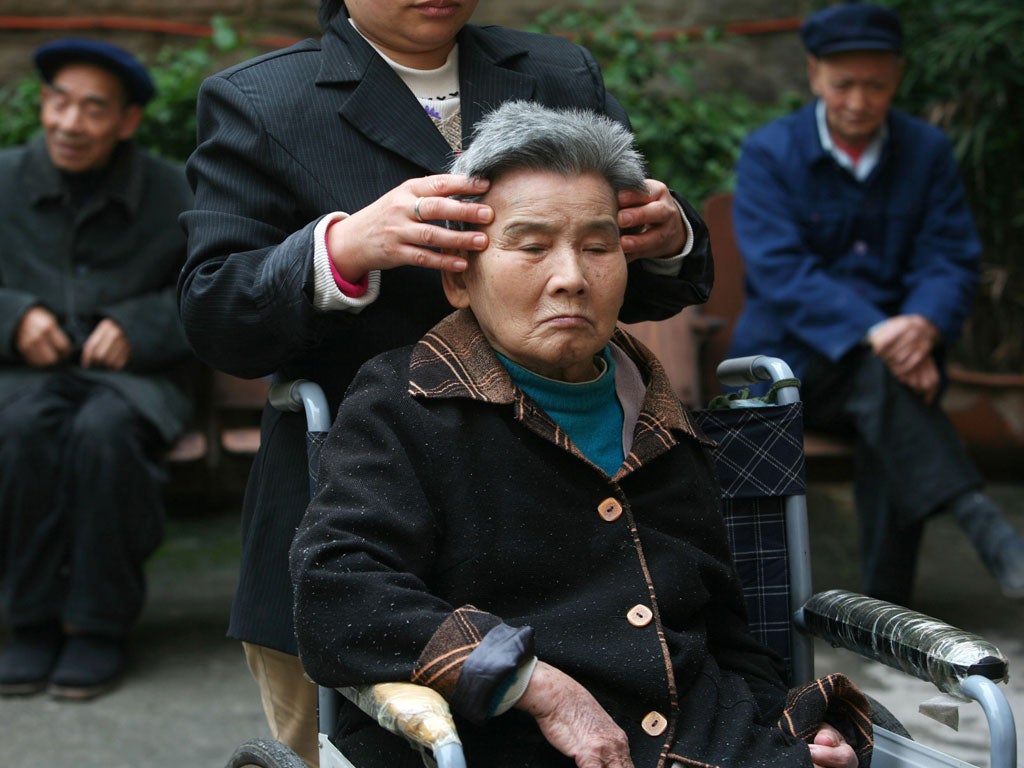An attendant gives massage to a senior citizen in an elder care center on October 16, 2007 in Chongqing Municipality, China.