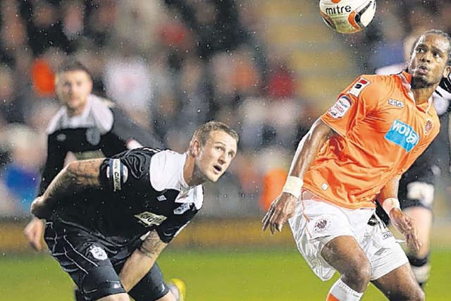 Nathan Delfouneso, of Blackpool, competes with Peter Clarke