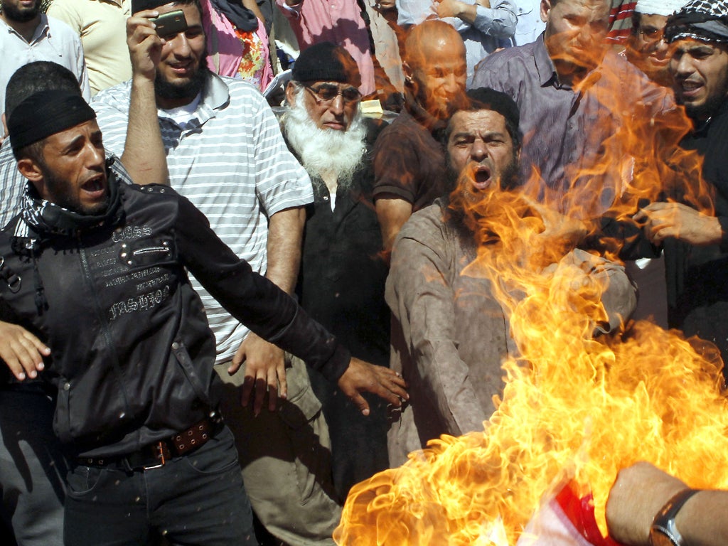 Jordanian protesters burn a US flag during a protest against an amateur film mocking Islam near the US embassy in Amman.