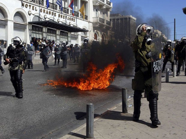 A molotov cocktail explodes beside riot police officers near Syntagma square during a 24-hour strike in Athens