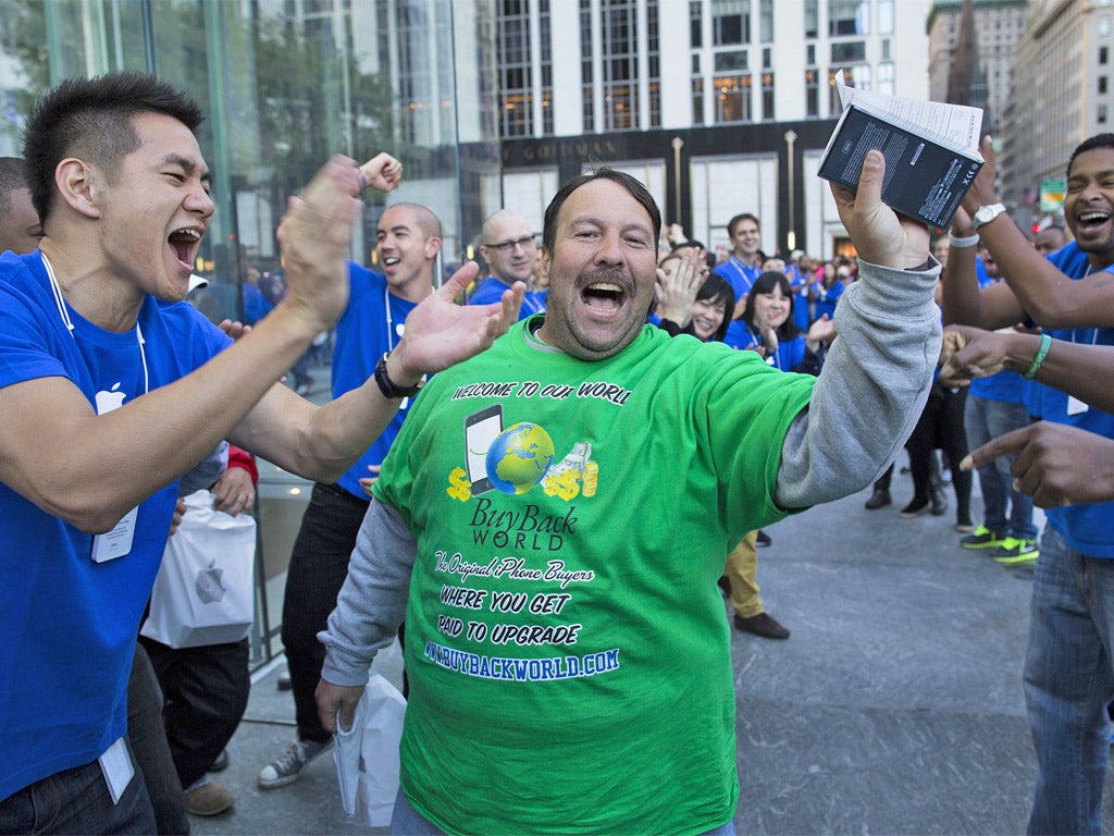 A happy customer is cheered on as he celebrates with his newly purchased iPhone 5 in hand outside the Fifth Avenue Apple store, in New York