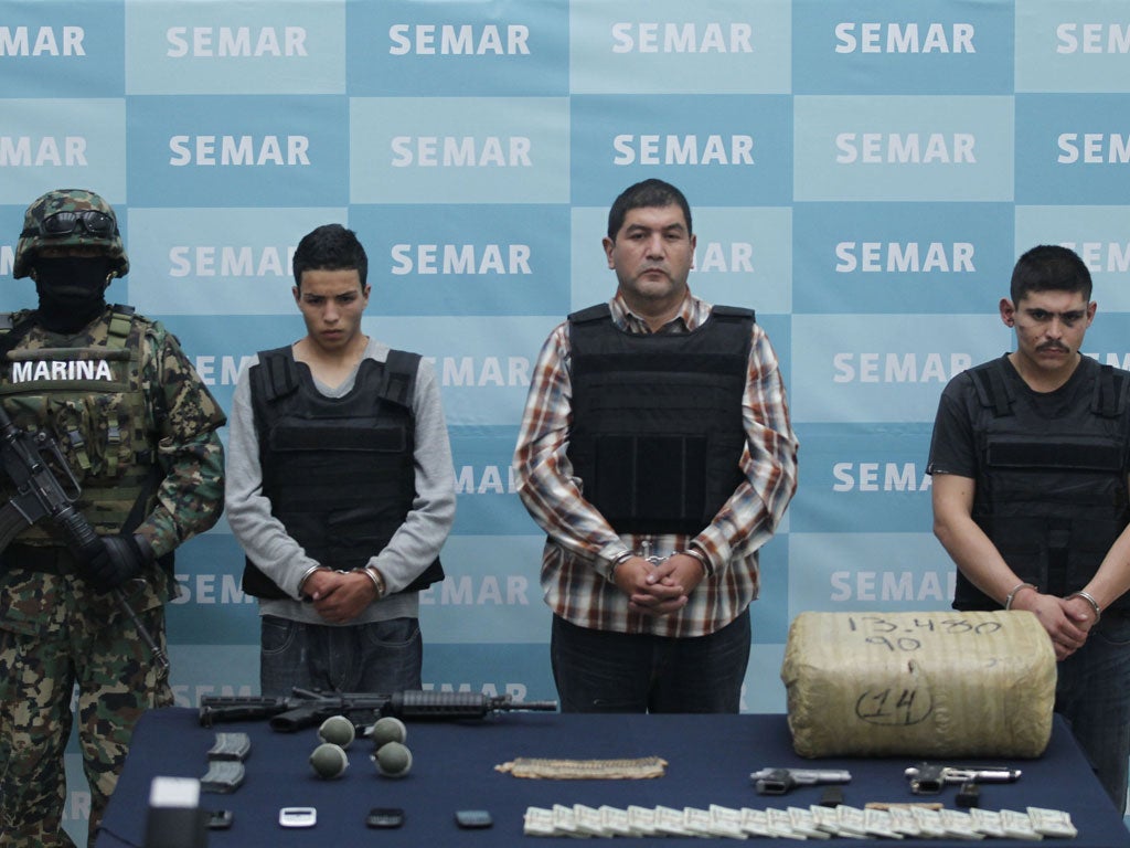 Ivan Velázquez Caballero, in the checked shirt, and two suspects are paraded with drugs and weapons seized during their arrest