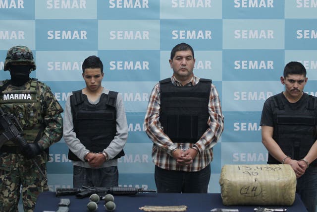 Ivan Velázquez Caballero, in the checked shirt, and two suspects are paraded with drugs and weapons seized during their arrest