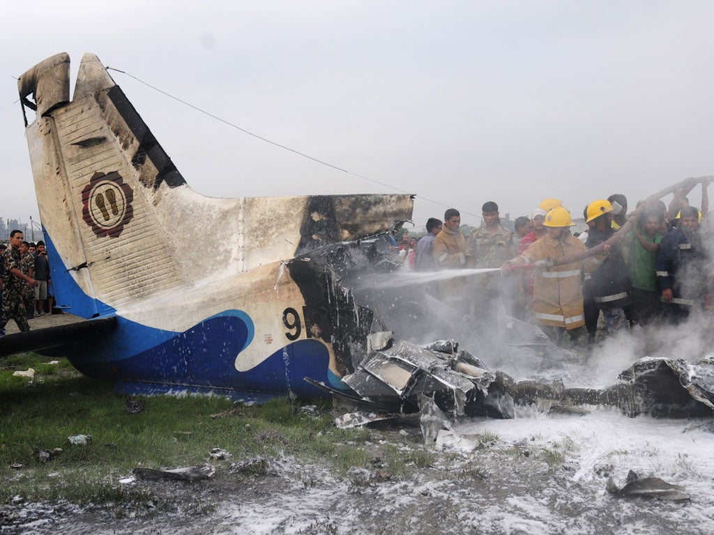Nepalese fireman and volunteers help extinguish flames from the wreckage of the Sita airplane after it crashed in Manohara, Bhaktapur on the outskirts of Kathmandu on September 28, 2012