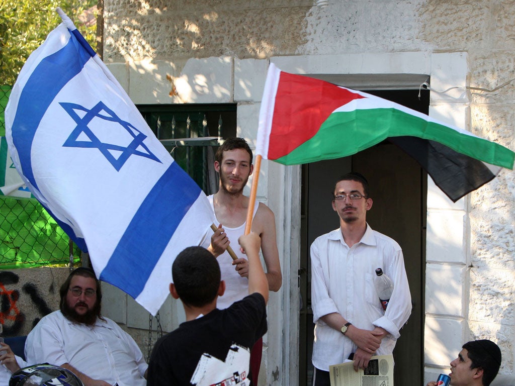 A Palestinian boy waves his national flag in front of Jewish settlers waving the Israeli flag on September 16, 2011 at a house occupied by settlers belonging to the Palestinian al-Kurd family, in east Jerusalem's Sheikh Jarrah neighborhood.