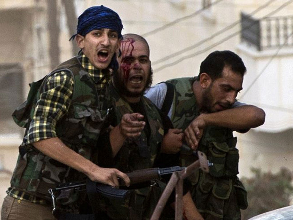 An injured rebel is helped away during fighting in Aleppo