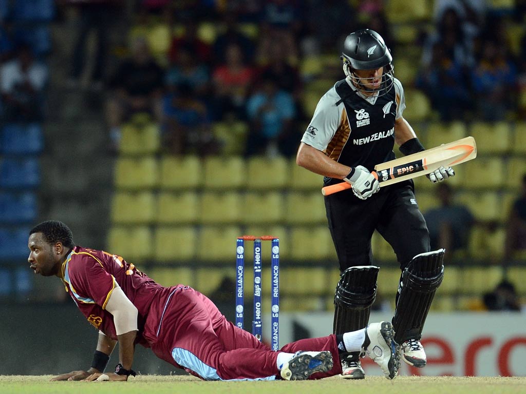 West Indies bowler Kieron Pollard (R) dives to stop a shot as New Zealand cricketer Ross Taylor (L) looks on