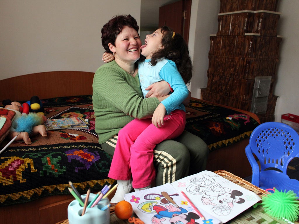 An orphaned Romanian girl (R) jokes with her childminder near Arges, southern Romania, on November 27, 2009