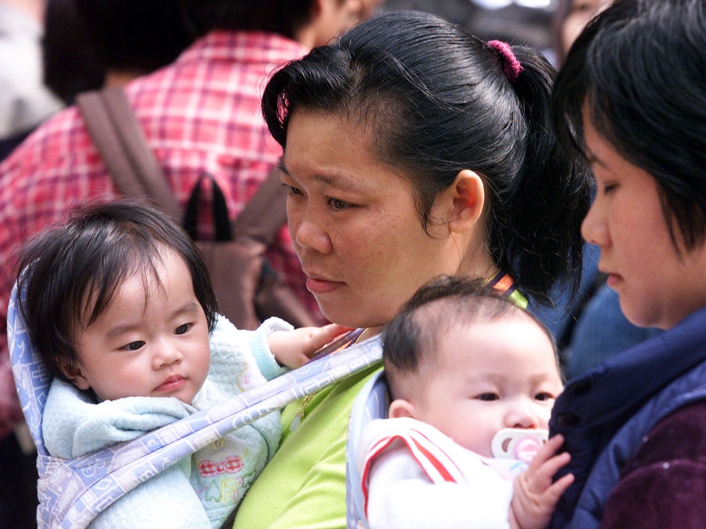 Women holding their babies wait with crowds of people outside Hong Kong's immigration headquarters 01 February