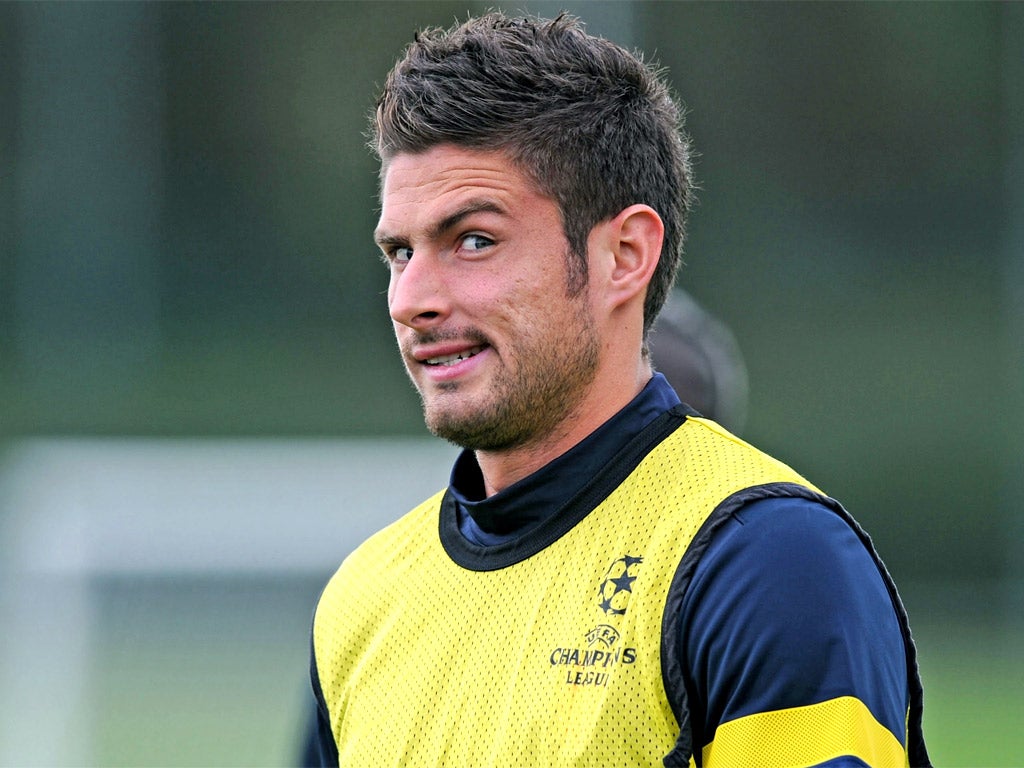 Olivier Giroud casts a quizzical eye towards photographers at a training session watched by Michael Johnson