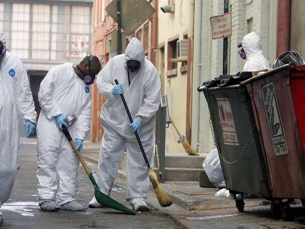 Men wear protective suits as they clean the streets of garbage September 17, 2005, New Orleans, Louisiana.