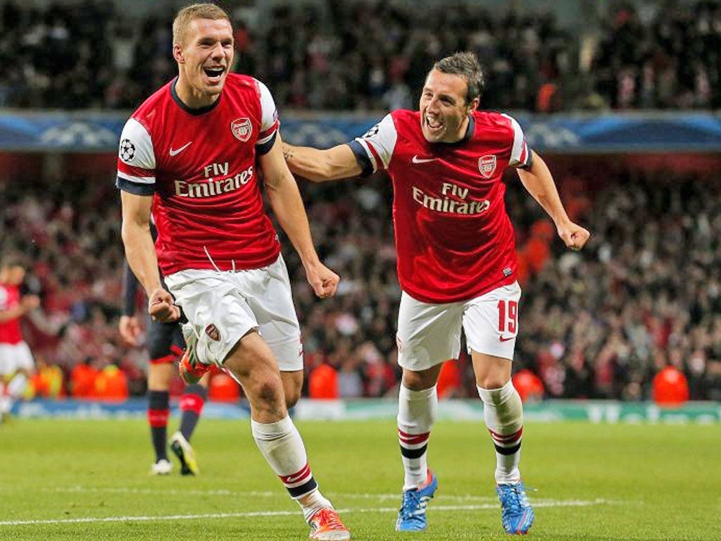 Lukas Podolski celebrates scoring the second Arsenal goal with Santi Cazorla during the UEFA Champions League