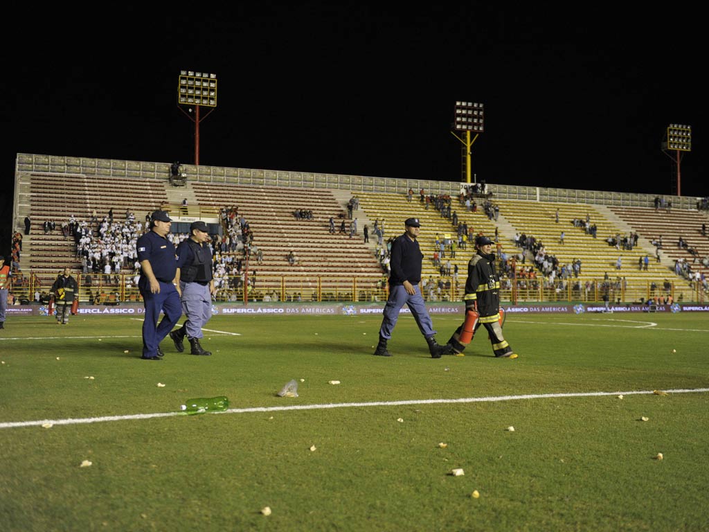 Firefighters walk across the pitch after Argentina's supporters threw 'chipas' after the announcing of the suspension of the friendly