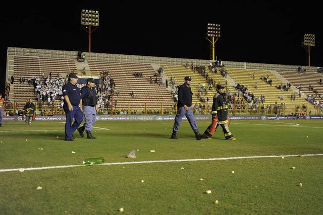 Firefighters walk across the pitch after Argentina's supporters threw 'chipas' after the announcing of the suspension of the friendly 