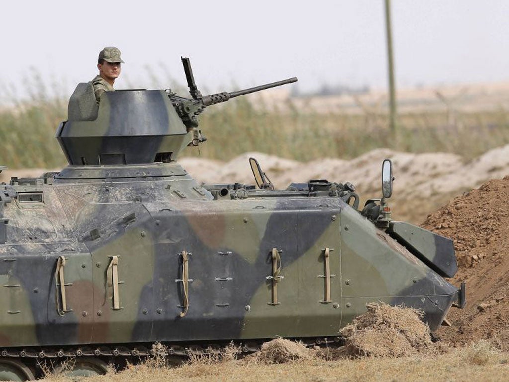 A Turkish soldier stands guard in an armoured personnel carrier  on the Turkish-Syrian border