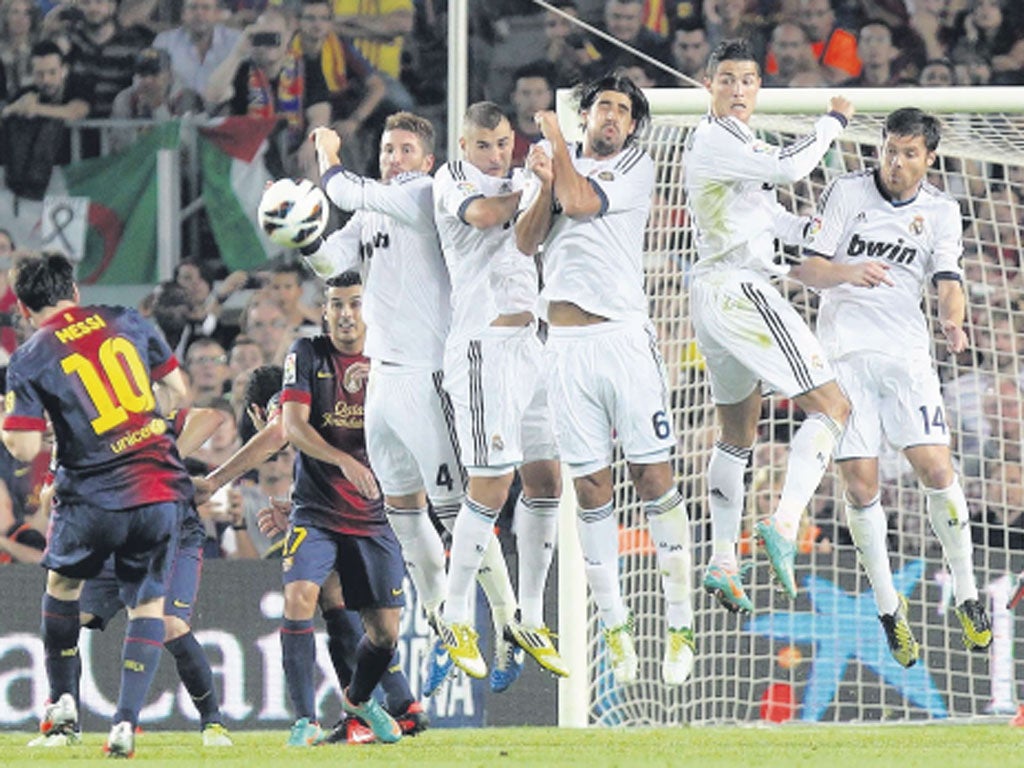 Barcelona’s Lionel Messi curls a ball over the Madrid wall to score his second goal