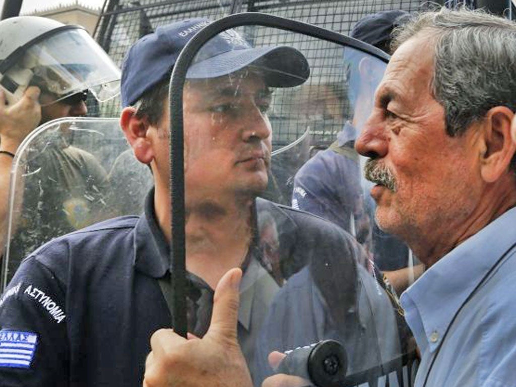 A pensioner confronts riot police in scuffles over austerity measures near EU offices in Athens yesterday