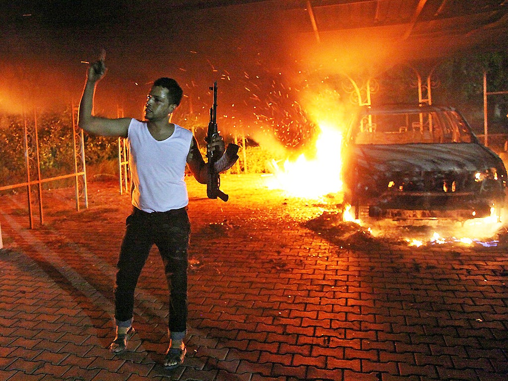 11 September 2012: An armed man waves his rifle as buildings and cars are engulfed in flames in the US consulate compound in Benghazi