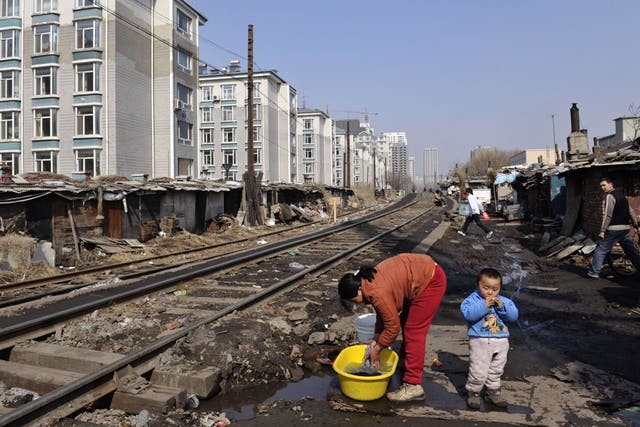 A woman washes clothes beside a railway at a shanty town where residents will move into low-rent apartments provided by the government on March 11, 2009 in Shenyang of Liaoning Province, China.