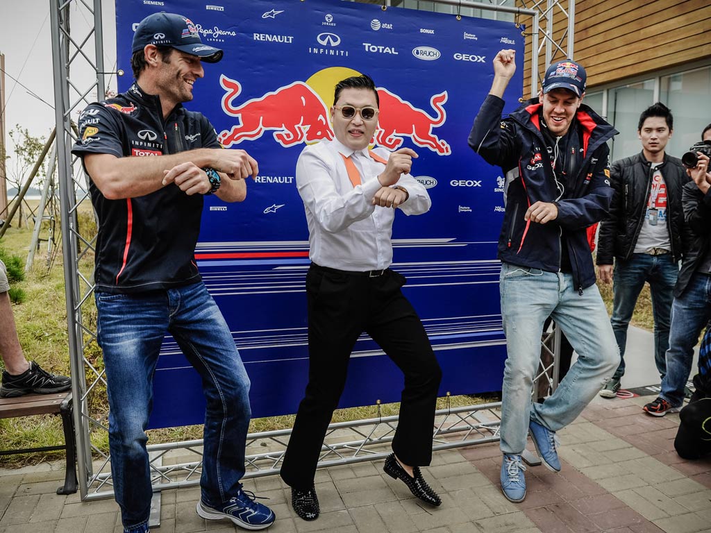 K-Pop star Psy (C) performs the 'Gangnam style' dance with Red Bull-Renault drivers Mark Webber and Sebastian Vettel