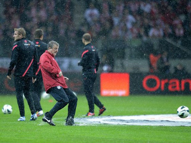 England manager Roy Hodgson tests the condition of the pitch in the pouring rain before the World Cup Group H Qualifying match at the National Stadium in Warsaw