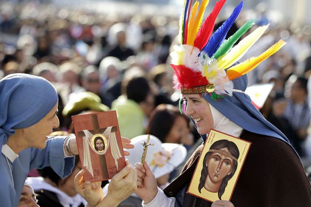 Nuns hold images of Kateri Tekakwitha, who died serving the church in Quebec in Canada, as they wait for the start of a canonisation ceremony celebrated by the Pope at the Vatican’s St Peter’s Square