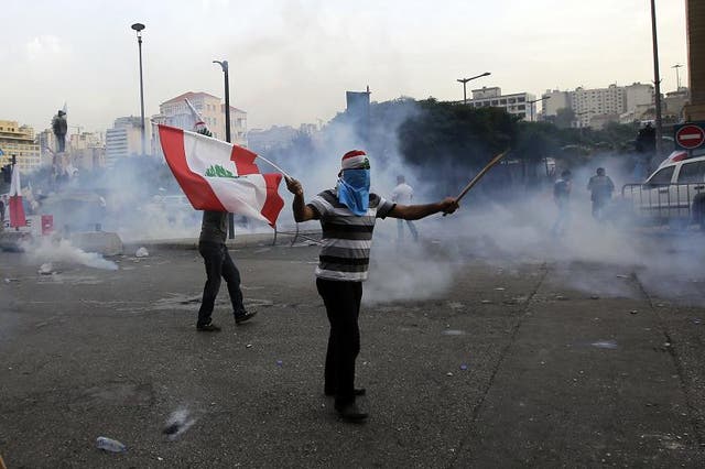 A Lebanese supporter of the March 14 movement, which opposes the Syrian regime of President Bashar al-Assad, demonstrates waving his national flag, as other protesters tried to storm the governmental palace, after the funeral of top intelligence chief Gen