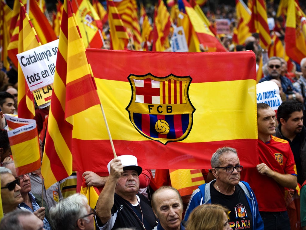 Anti-separatist Catalans hold a Spanish flag with the FC Barcelona's coat of arms during a demonstration on Spain National Day on October 12, 2012 in Barcelona, Spain