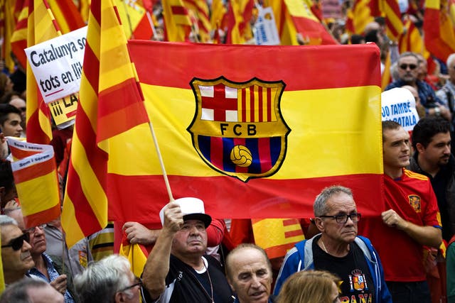 Anti-separatist Catalans hold a Spanish flag with the FC Barcelona's coat of arms during a demonstration on Spain National Day on October 12, 2012 in Barcelona, Spain