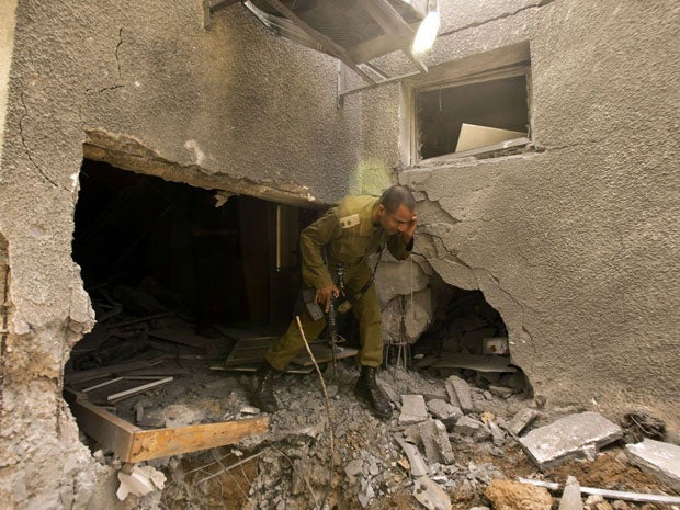 An Israeli soldier inspects the damage to a house following a rocket attack on the the Israeli Kibbutz Beeri from the neighbouring Gaza Strip