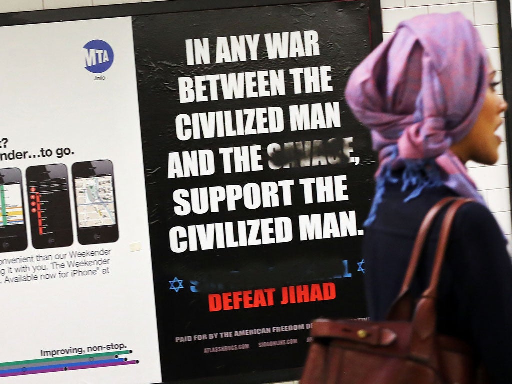 People walk by a controversial ad, which has already been defaced, that condemns radical Islam in a New York subway station on September 27, 2012 in New York City.
