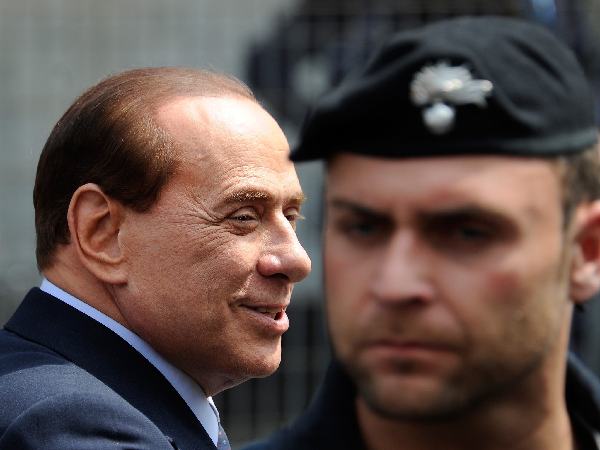 Silvio Berlusconi passes a policeman outside Milan's justice court