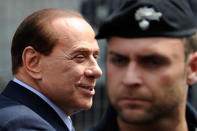 Silvio Berlusconi passes a policeman outside Milan's justice court