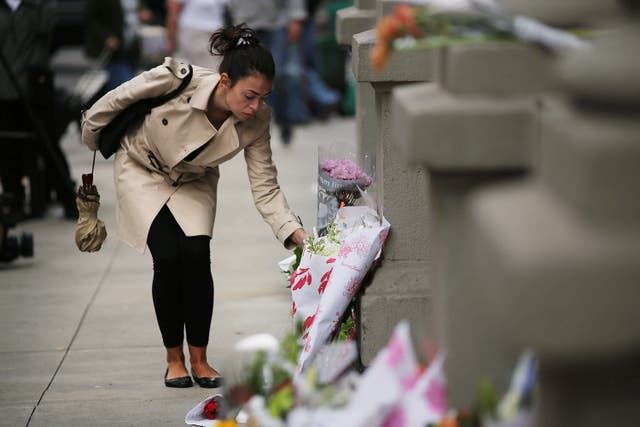 A woman leaves flowers at the Upper West Side apartments where two children were fatally stabbed