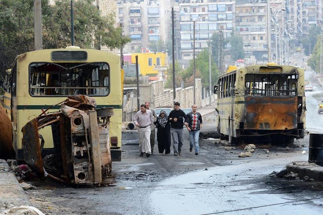 Syrian civilians walk past burnt buses near a checkpoint in the northern city of Aleppo. Outbursts of fighting threatened to undermine a fragile ceasefire that took effect in Syria after President Bashar al-Assad's regime and the main rebel force agreed t