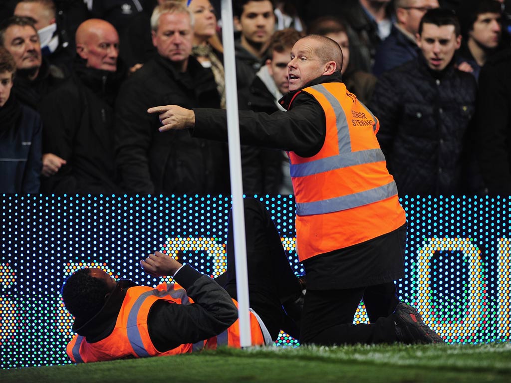 A steward is helped by a fellow steward during the Barclays Premier League match between Chelsea and Manchester United at Stamford Bridge