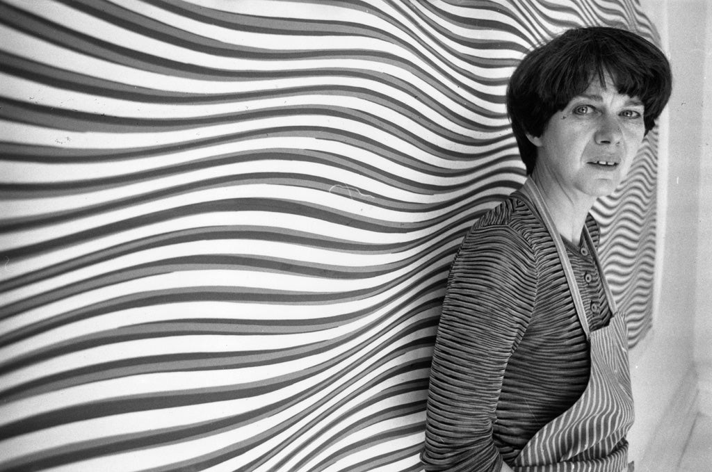 26th July 1979: Bridget Riley, British painter and leading figure in the Op Art movement, standing in front of one of her curving 'line' paintings at her studio.