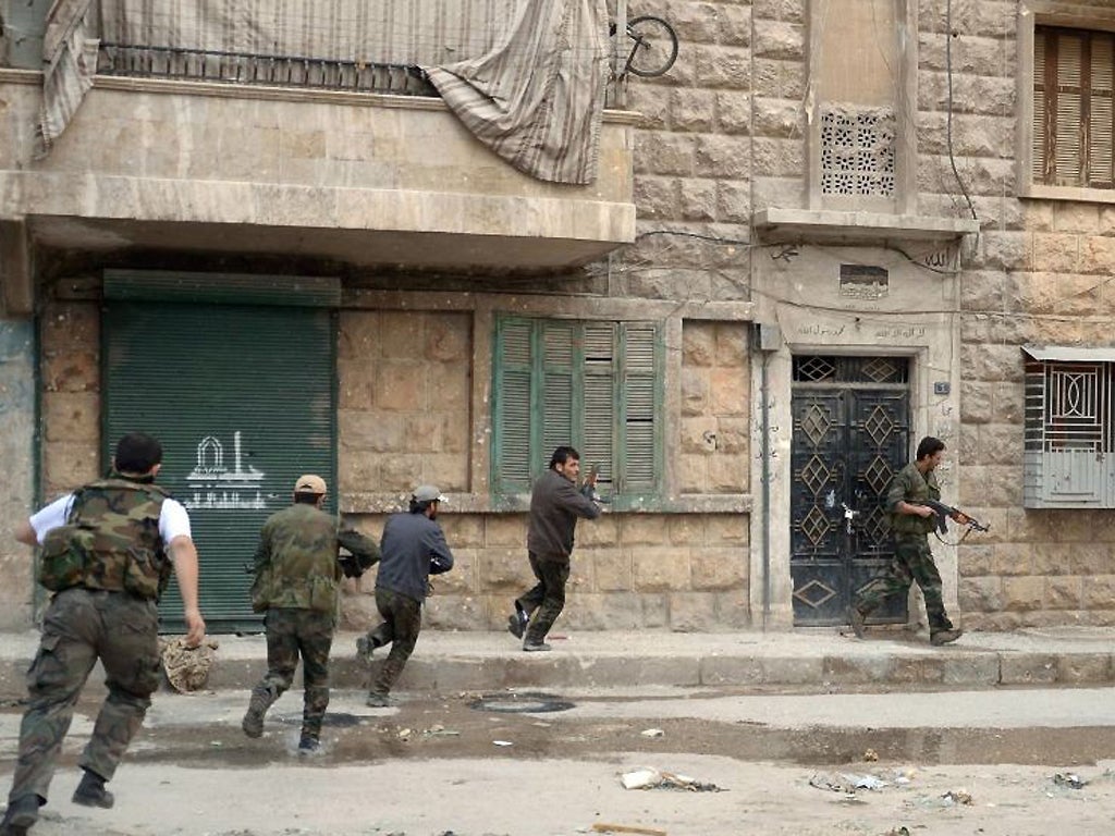 Pro-government forces run across the street in the Suleiman al-Halabi nieghbourhood, now under full army control according to state media, of the northern Syrian city of Aleppo on 30 October 2012 during clashes with Syrian opposition fighters