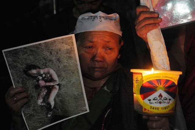 An exile Tibetan woman cries while holding a photograph of a Tibetan youth from eastern Tibet who on September 29 allegedly burned himself in protest against Chinese rule, during a candlelight vigil in McLeod Ganj, Dharamsala, on September 30, 2012. Twent