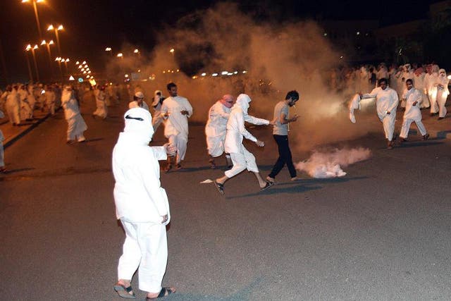 Protesters run for cover as Kuwait riot police used stun grenades and tear gas to disperse thousands of angry demonstrators who marched on the central prison where a leading opposition figure is detained, in Kuwait City on October 31, 2012. The protest came hours after the public prosecutor extended the detention of Mussallam al-Barrak for 10 days over remarks deemed critical of the emir, in a crackdown on dissent ahead of snap December 1 elections.