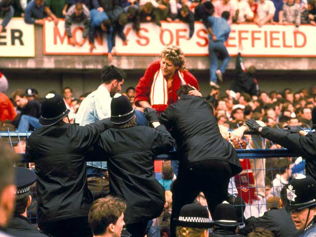 A fan is helped to safety by police officers at the Hillsborough stadium